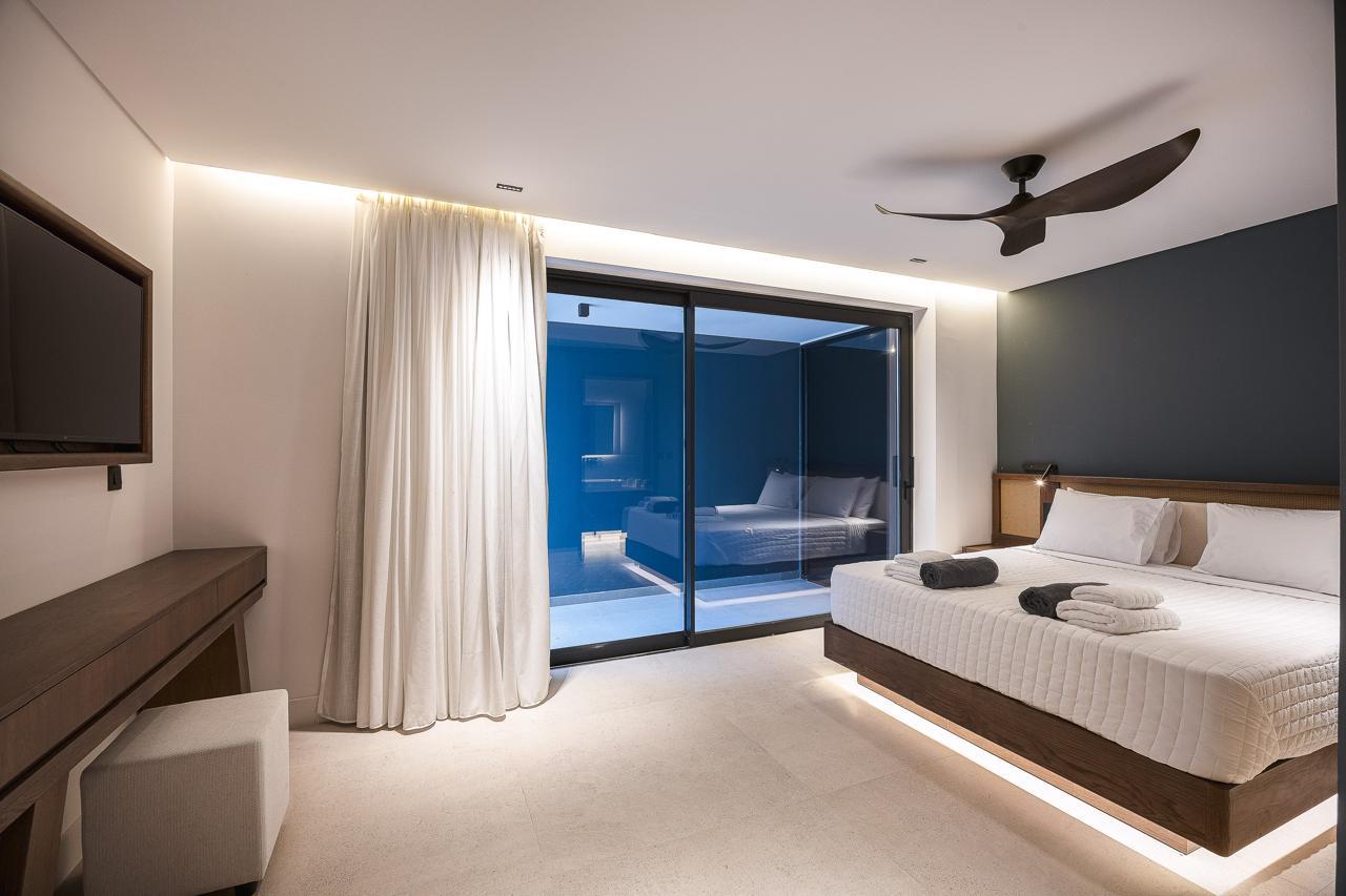 The charcoal suite at dusk with its lit courtyard beyond the glass